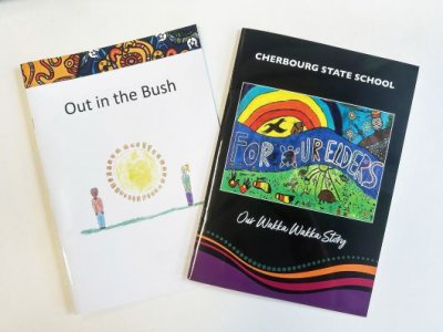 Two Indigenous story books fanned out on a white desktop. One is titled Out in the Bush, the other is For Our Elders.